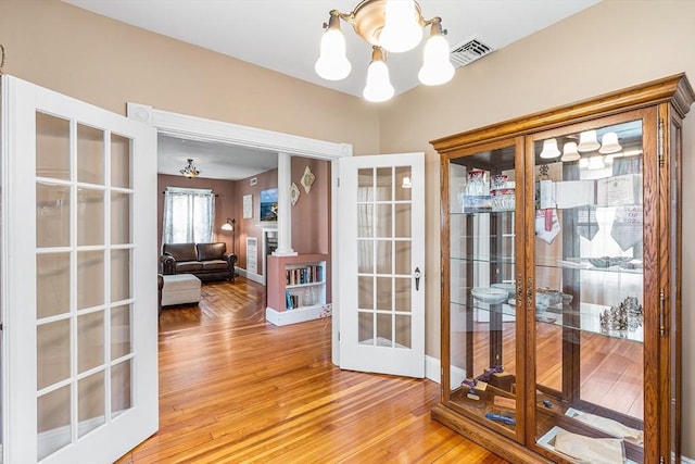 doorway to outside with light wood-style floors, visible vents, french doors, and a chandelier