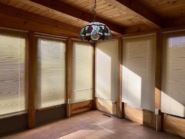 unfurnished sunroom with beamed ceiling