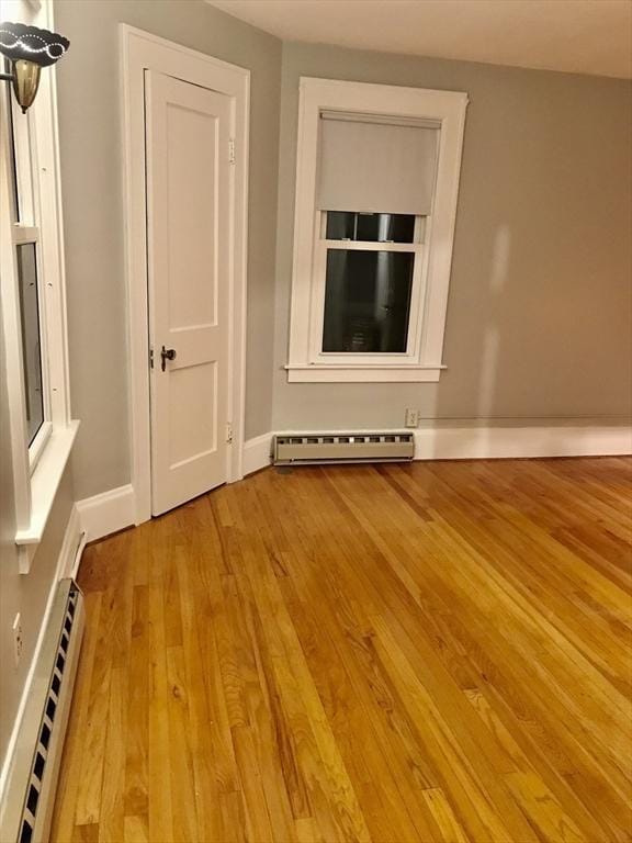 spare room featuring baseboards, wood finished floors, and a baseboard radiator