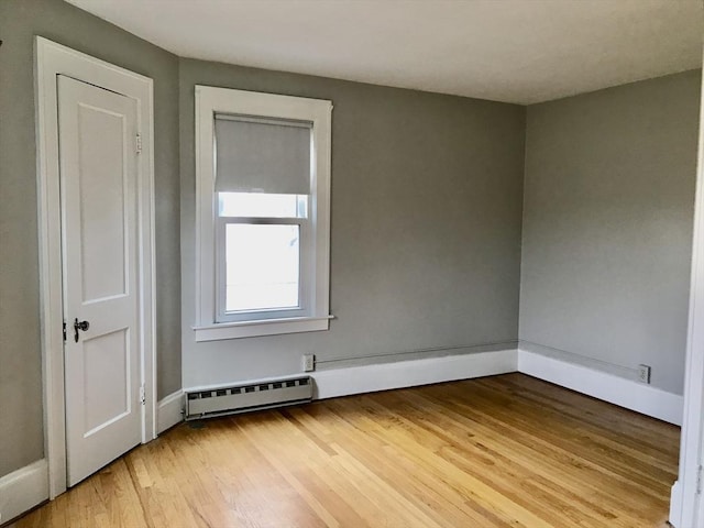 empty room with baseboards, wood finished floors, and baseboard heating