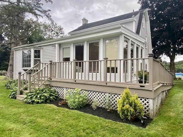 rear view of house with a lawn, a chimney, and a wooden deck