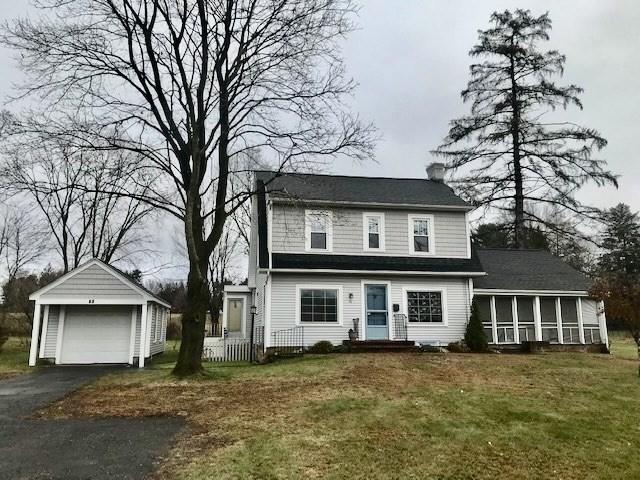 view of front of property featuring a garage, a sunroom, a front lawn, and an outbuilding