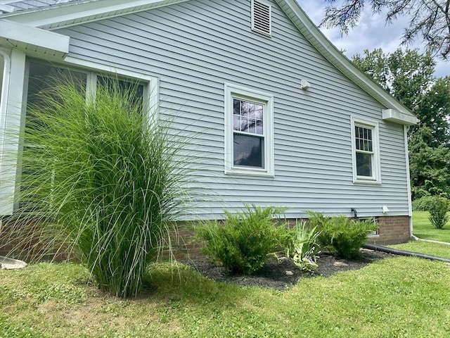 view of side of home with crawl space and a yard