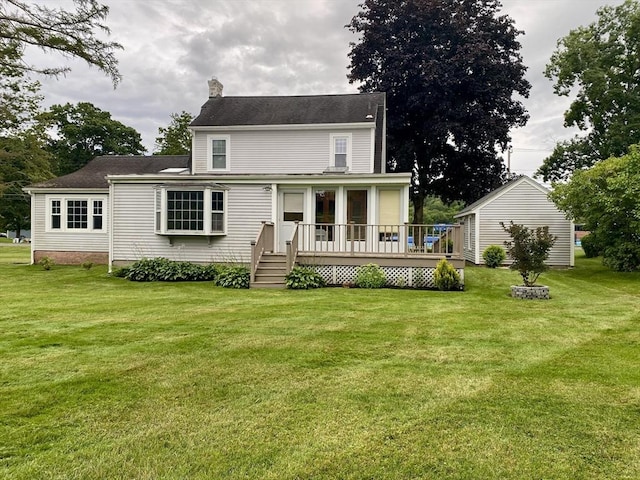 back of house featuring a lawn, a chimney, and a deck