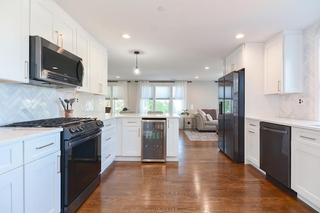 kitchen with beverage cooler, open floor plan, a peninsula, white cabinets, and stainless steel appliances