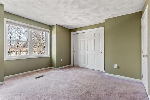 unfurnished bedroom with visible vents, baseboards, carpet, a closet, and a textured ceiling