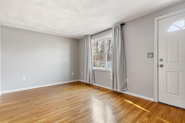 entryway with baseboards, plenty of natural light, visible vents, and light wood-style flooring