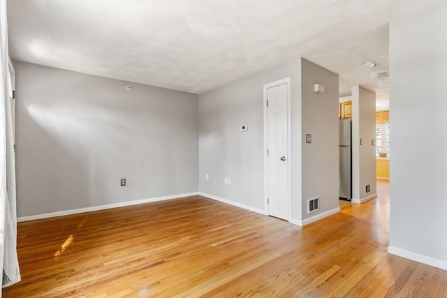 empty room featuring visible vents, baseboards, and light wood-type flooring