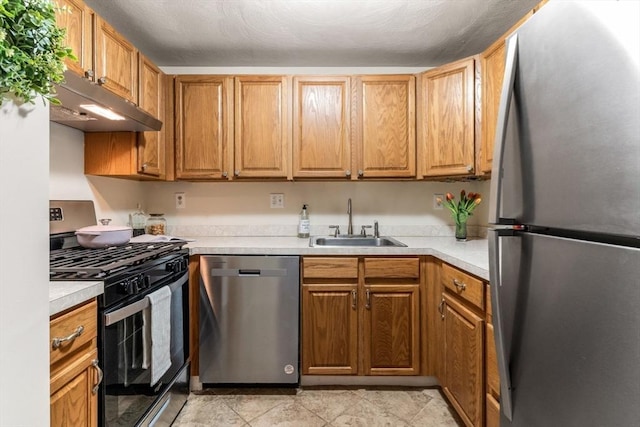 kitchen featuring a sink, stainless steel appliances, under cabinet range hood, and light countertops