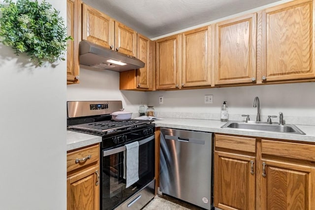 kitchen featuring under cabinet range hood, appliances with stainless steel finishes, light countertops, and a sink