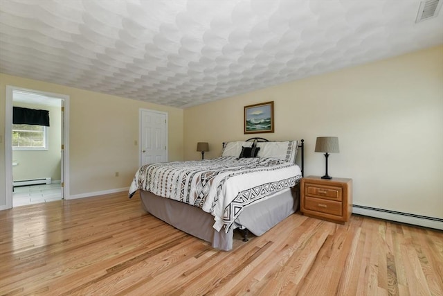 186 Mitchell G Dr, Tewksbury, MA 01876 - bedroom with baseboard heating, light wood-style floors, baseboards, and a baseboard radiator