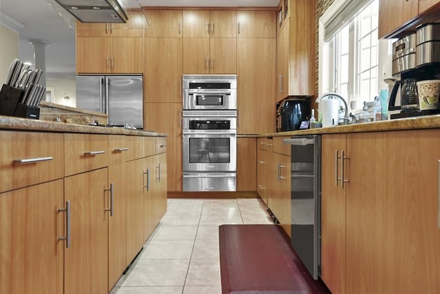 kitchen with stone counters, extractor fan, beverage cooler, light tile patterned floors, and stainless steel appliances