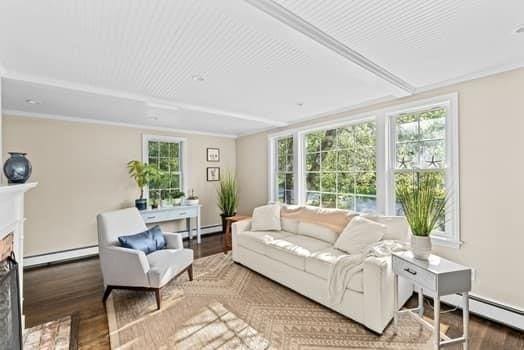 28 Christopher Ln, Scituate, MA 02066 - living area with a baseboard radiator, wood finished floors, and a fireplace with flush hearth