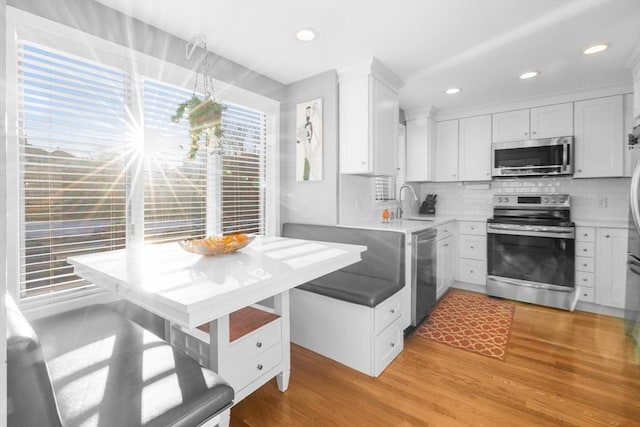 kitchen with light hardwood / wood-style flooring, white cabinetry, stainless steel appliances, and tasteful backsplash