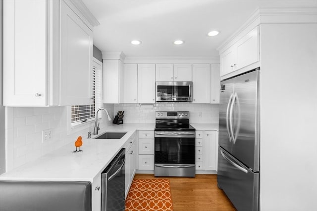 kitchen with tasteful backsplash, white cabinetry, sink, and stainless steel appliances