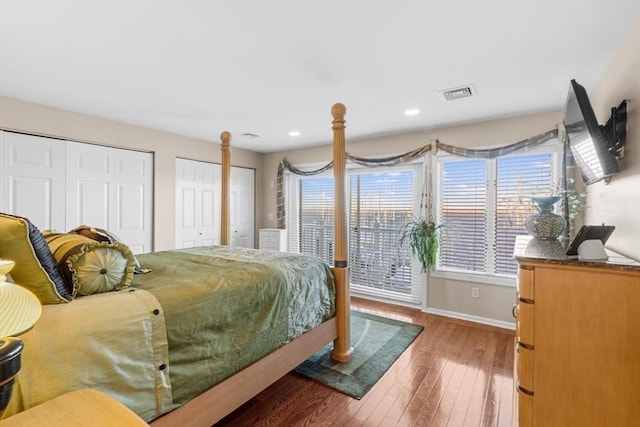 bedroom with access to exterior, hardwood / wood-style floors, and two closets