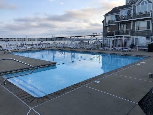 view of pool with a water view and a patio