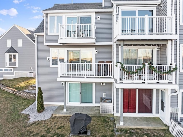 back of property featuring a lawn, a balcony, and a patio