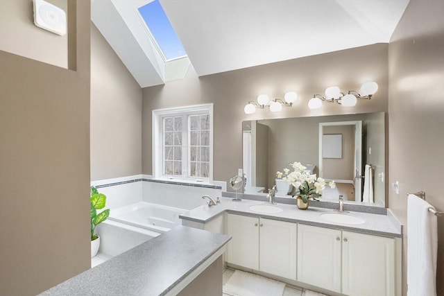 full bathroom featuring a sink, a bath, vaulted ceiling with skylight, and double vanity