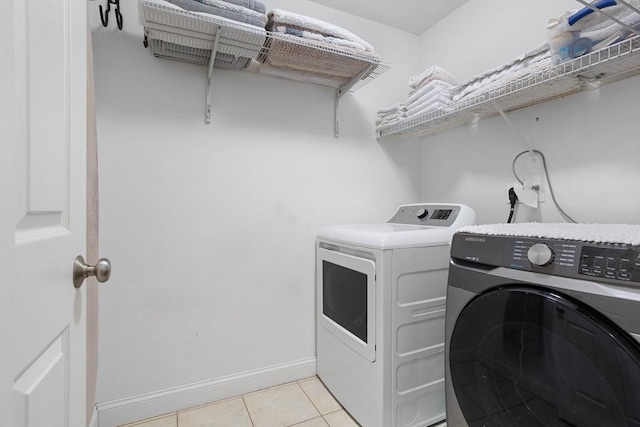 washroom with baseboards, laundry area, washing machine and dryer, and light tile patterned flooring