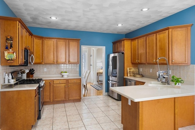 kitchen featuring brown cabinetry, a sink, light countertops, a peninsula, and stainless steel appliances