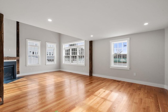 unfurnished living room featuring a large fireplace and light hardwood / wood-style floors