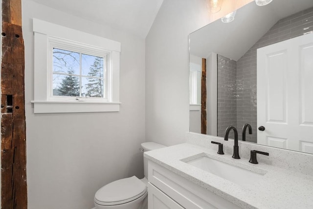 bathroom with lofted ceiling, toilet, and vanity