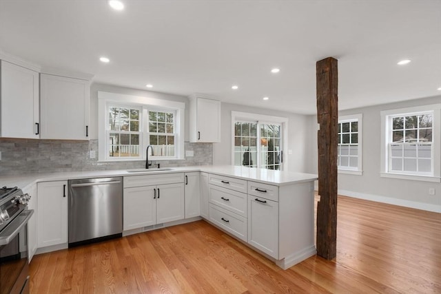 kitchen featuring appliances with stainless steel finishes, kitchen peninsula, white cabinets, and sink