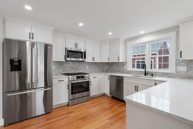 kitchen with appliances with stainless steel finishes, white cabinetry, tasteful backsplash, and sink