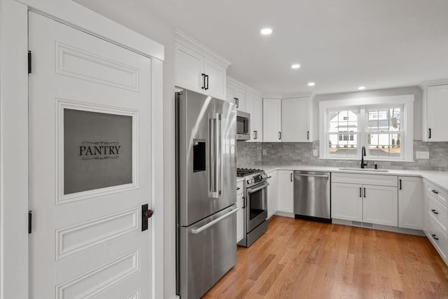 kitchen featuring appliances with stainless steel finishes, white cabinets, backsplash, and sink