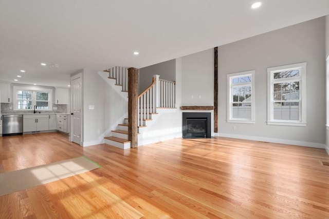 unfurnished living room with sink and light wood-type flooring