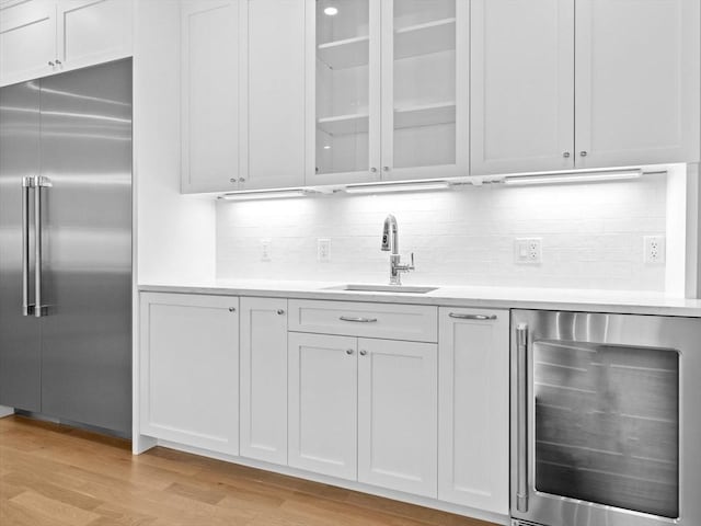 35 Lincoln St, Hopkinton, MA 01748 - kitchen with wine cooler, built in refrigerator, light countertops, light wood-style flooring, and glass insert cabinets