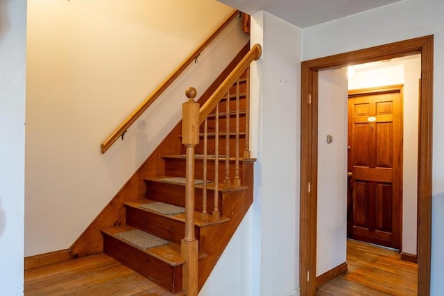 stairway with wood finished floors and baseboards