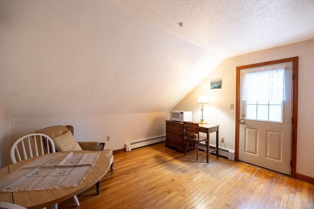 living area featuring light wood finished floors, a textured ceiling, a baseboard radiator, lofted ceiling, and baseboards