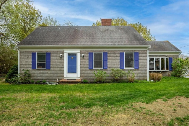 view of front facade with a chimney, a front lawn, and roof with shingles