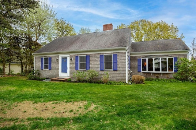 view of front of house with a chimney, a front yard, and roof with shingles
