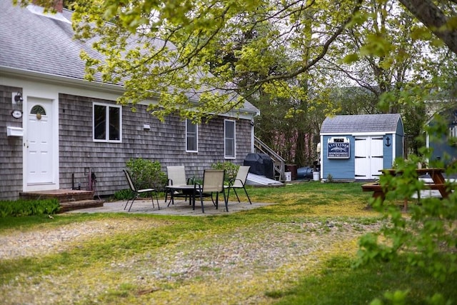 view of green lawn with a storage shed, an outdoor structure, and a patio