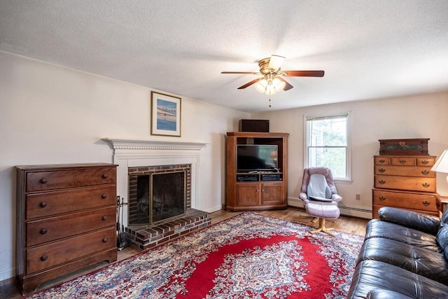 living area with a ceiling fan, wood finished floors, a fireplace, a baseboard radiator, and a textured ceiling