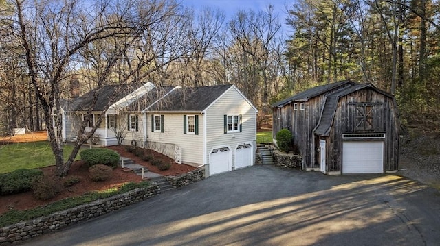 view of front facade featuring an outbuilding, a barn, driveway, and a garage