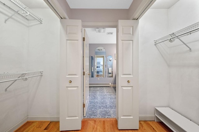 walk in closet with a baseboard heating unit and light wood-style flooring