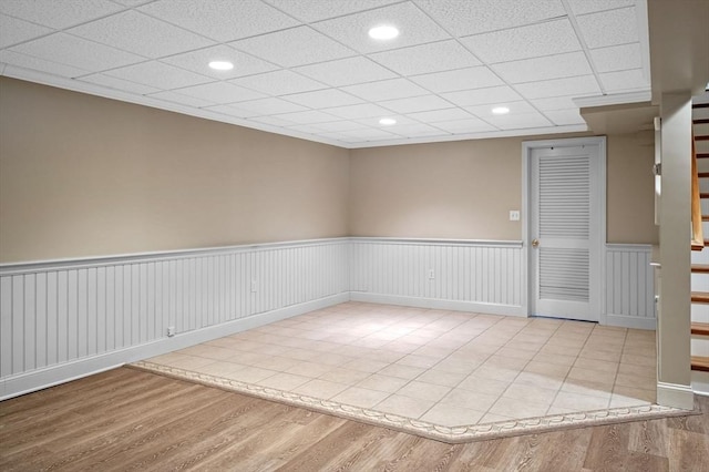 empty room featuring recessed lighting, wood finished floors, a drop ceiling, and wainscoting