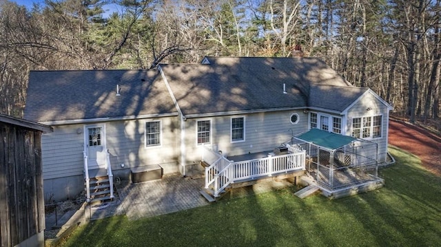 back of property with entry steps, a yard, a shingled roof, and a wooden deck