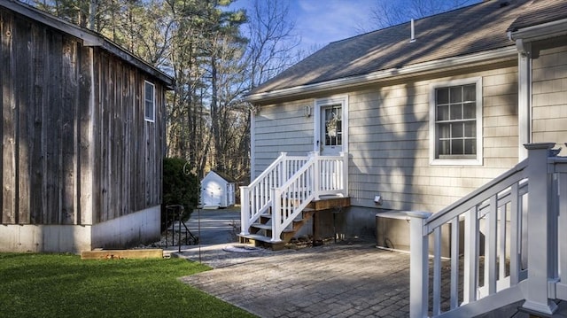 exterior space with a patio, a lawn, and a shingled roof