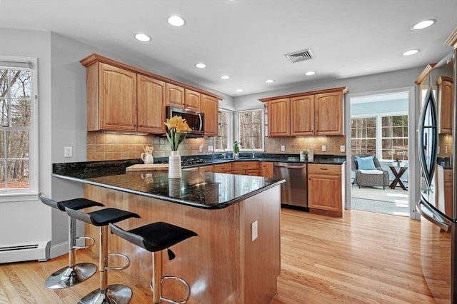 kitchen featuring a breakfast bar, plenty of natural light, light wood finished floors, and stainless steel appliances