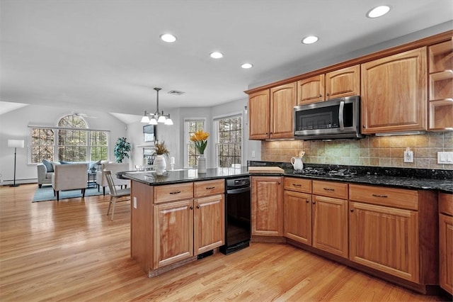 kitchen with a wealth of natural light, light wood-type flooring, black gas cooktop, stainless steel microwave, and backsplash