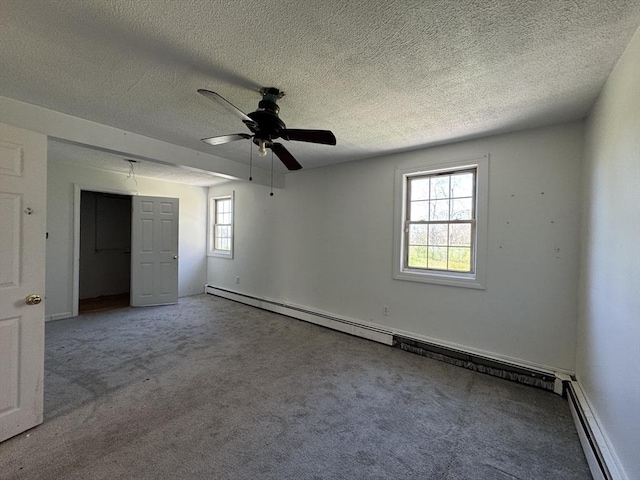 unfurnished bedroom with a baseboard radiator, multiple windows, carpet flooring, and a textured ceiling