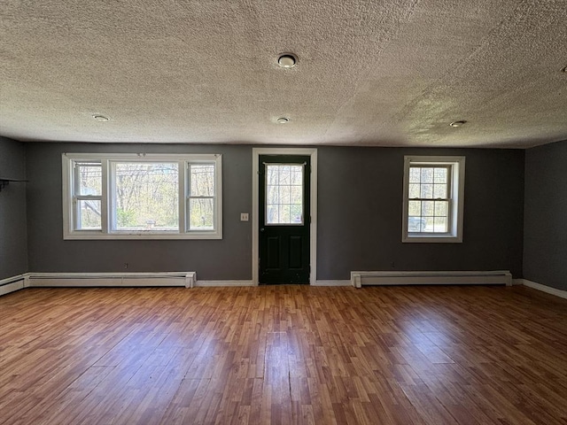 entryway featuring a baseboard radiator, wood finished floors, a textured ceiling, and baseboards