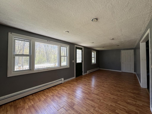 entrance foyer with a baseboard heating unit, wood finished floors, a textured ceiling, and baseboards