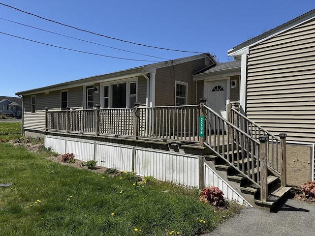 view of exterior entry with a lawn, an attached garage, and a deck