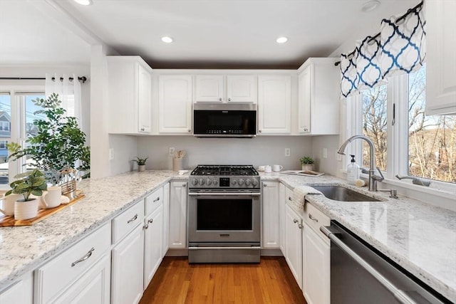 kitchen featuring sink, light hardwood / wood-style flooring, white cabinets, and appliances with stainless steel finishes